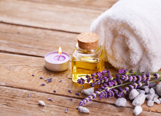 Spa still life with lavender oil, white towel and perfumed candle on natural wood